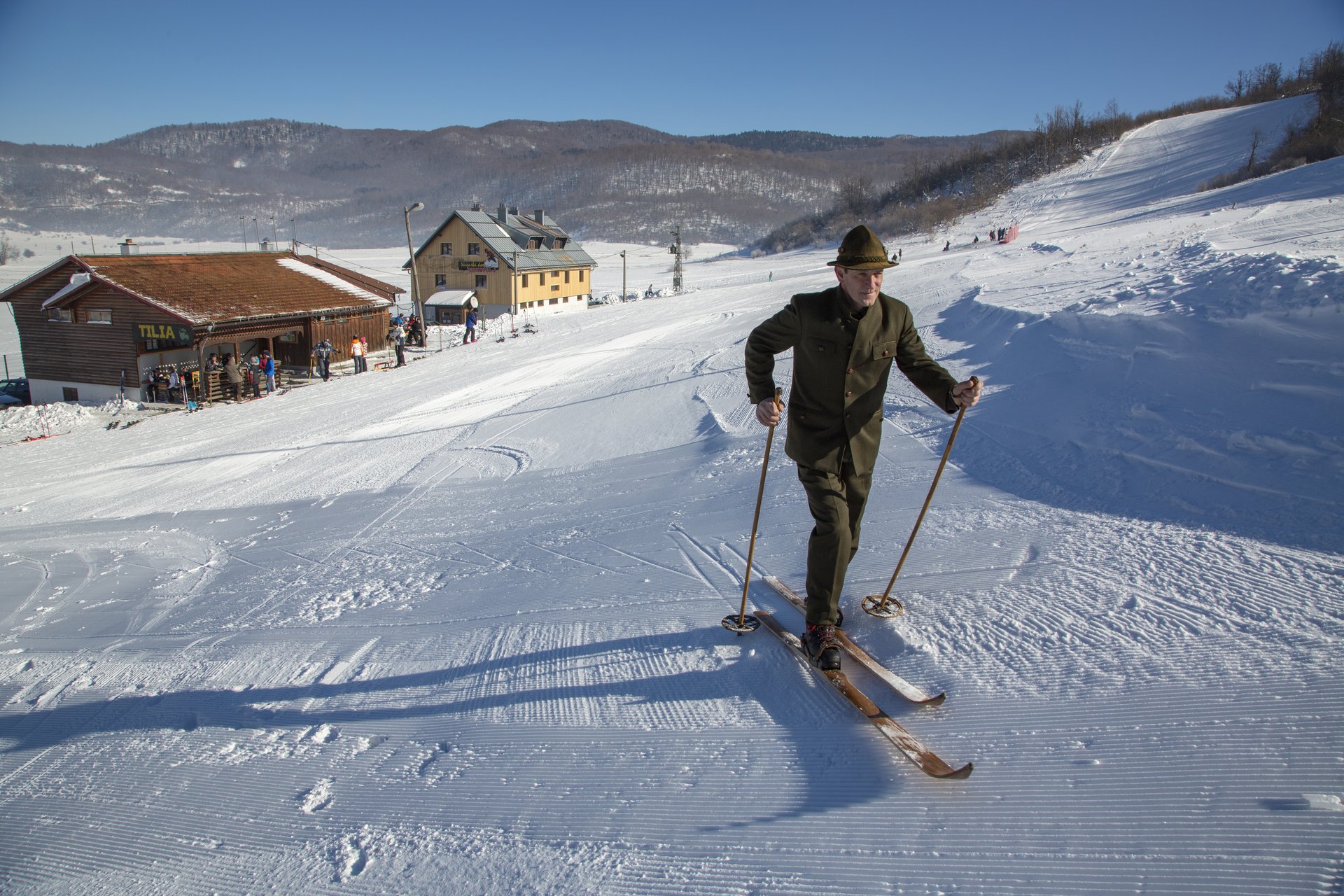 Skijaš ispred skijaškog doma na Čelimbaši za sunčanog dana